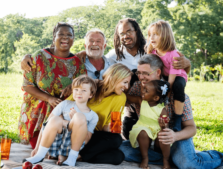 Multi-generational multi-cultural family together outside at a park having a picnic